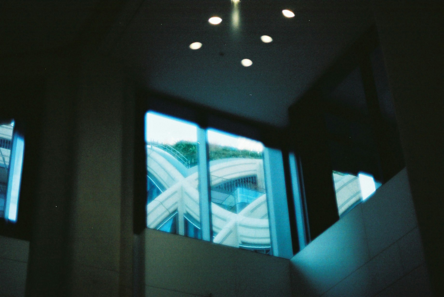 Vista de un edificio con fachada de vidrio y luces urbanas desde el interior de una habitación