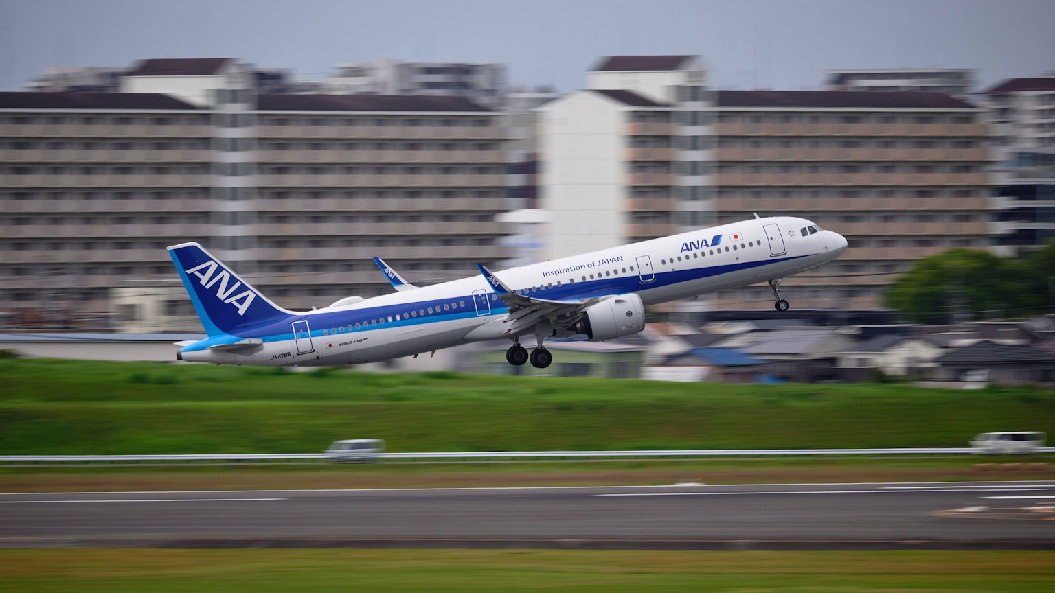 Avion ANA décollant de la piste avec des bâtiments en arrière-plan