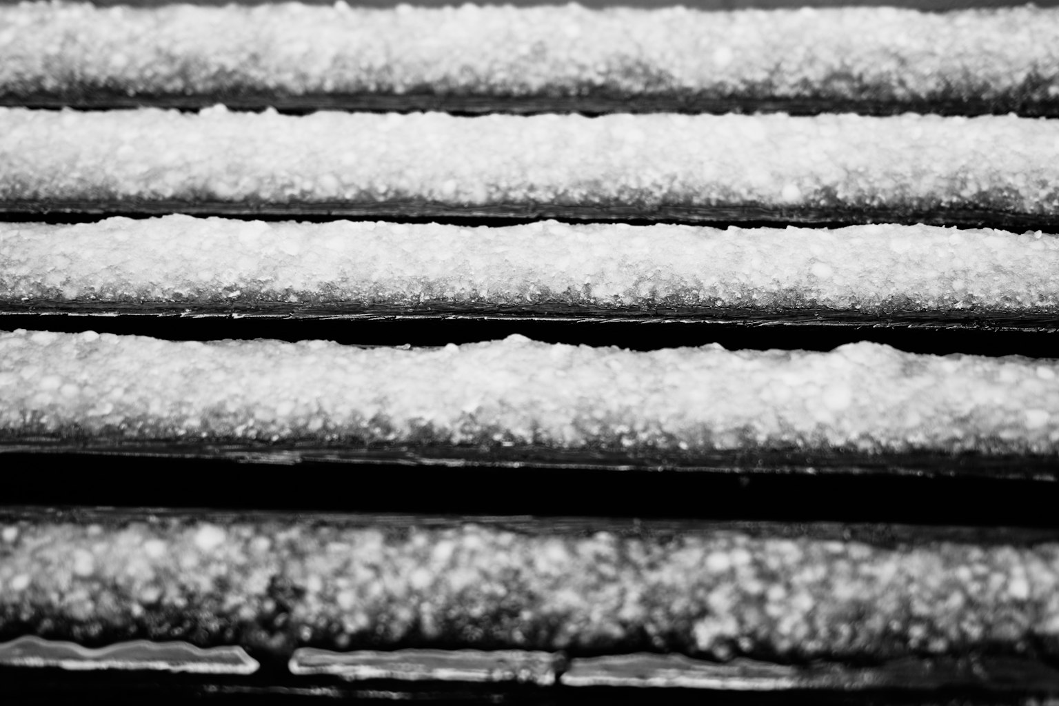 Primer plano de nieve acumulada en una superficie de rayas negras y blancas