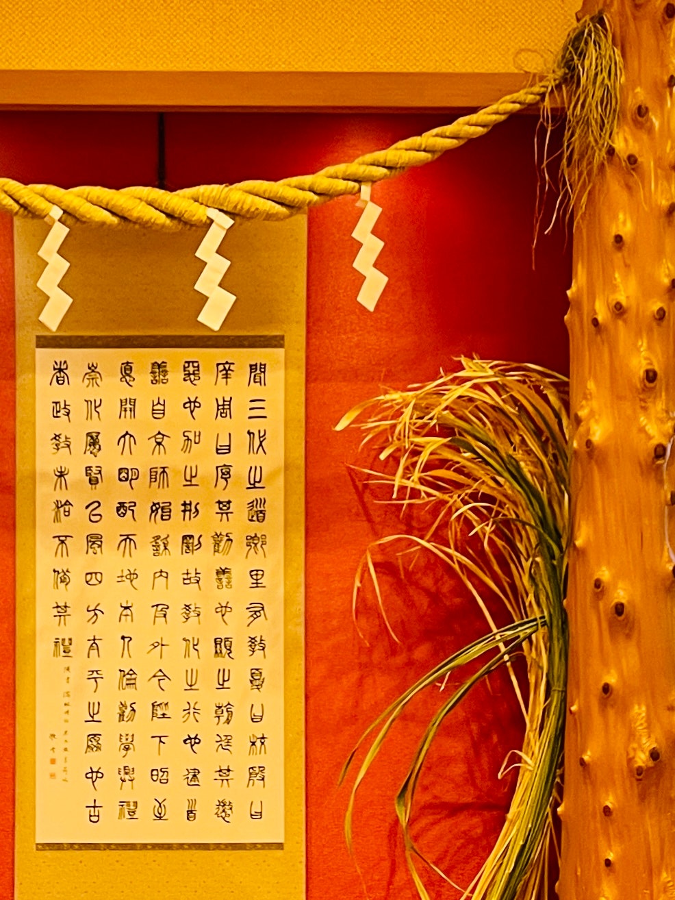 紅色牆面上的書法牌匾與繩飾的室內場景
