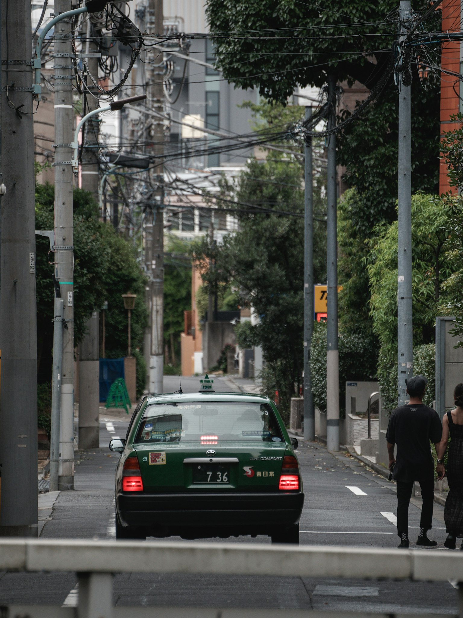Ein grünes Taxi fährt durch eine enge Gasse mit Fußgängern