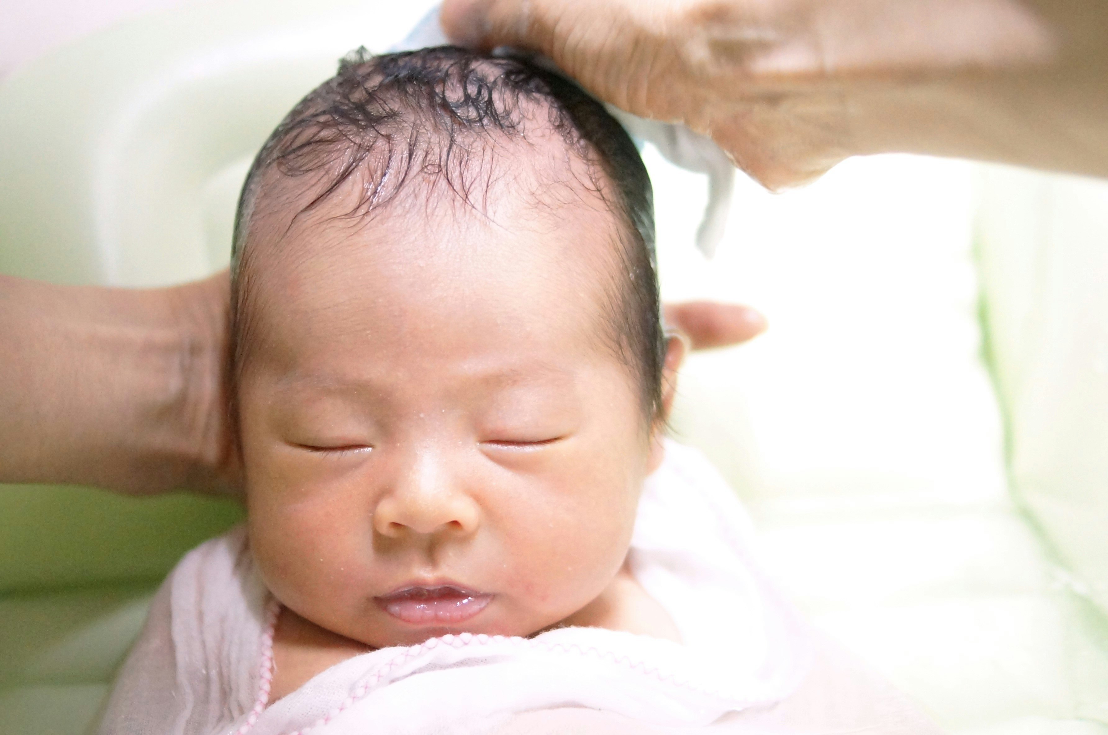 赤ちゃんの寝顔を抱き上げる手のある室内シーン