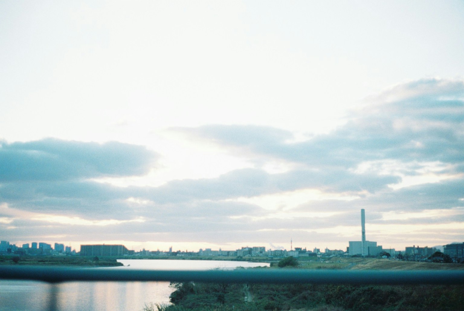 Landscape photo featuring a river and sky with a visible factory chimney