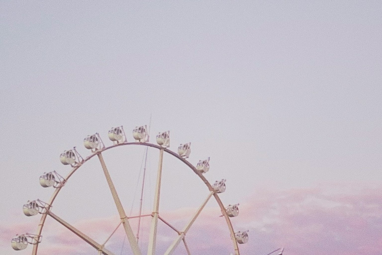 Ferris wheel against a soft pastel sky