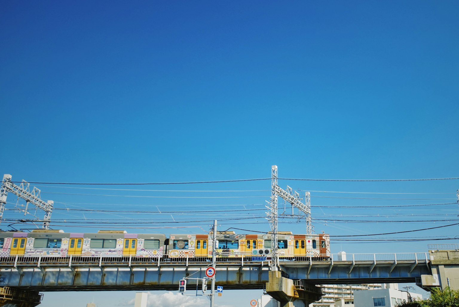 Un treno giallo che si muove su binari elevati sotto un cielo blu chiaro