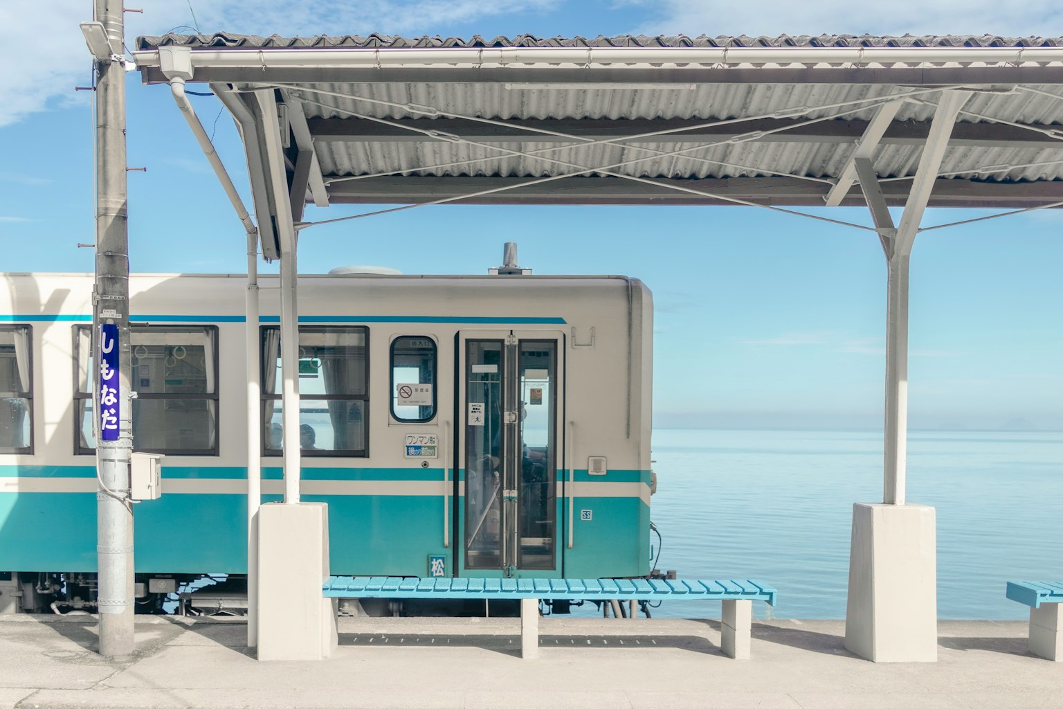 Un treno blu e bianco in una stazione sul mare