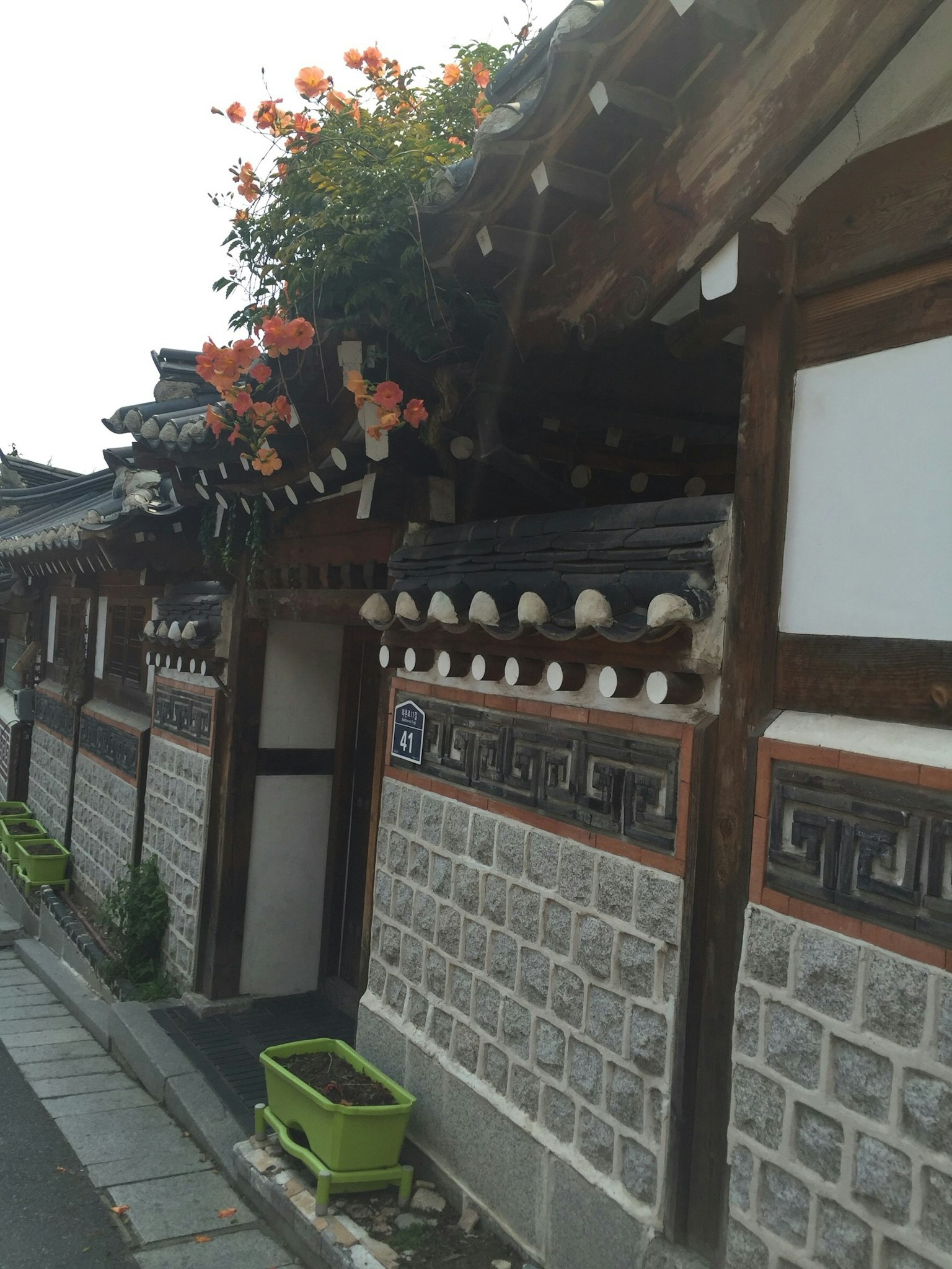 Extérieur d'une maison traditionnelle coréenne avec des fleurs sur le toit