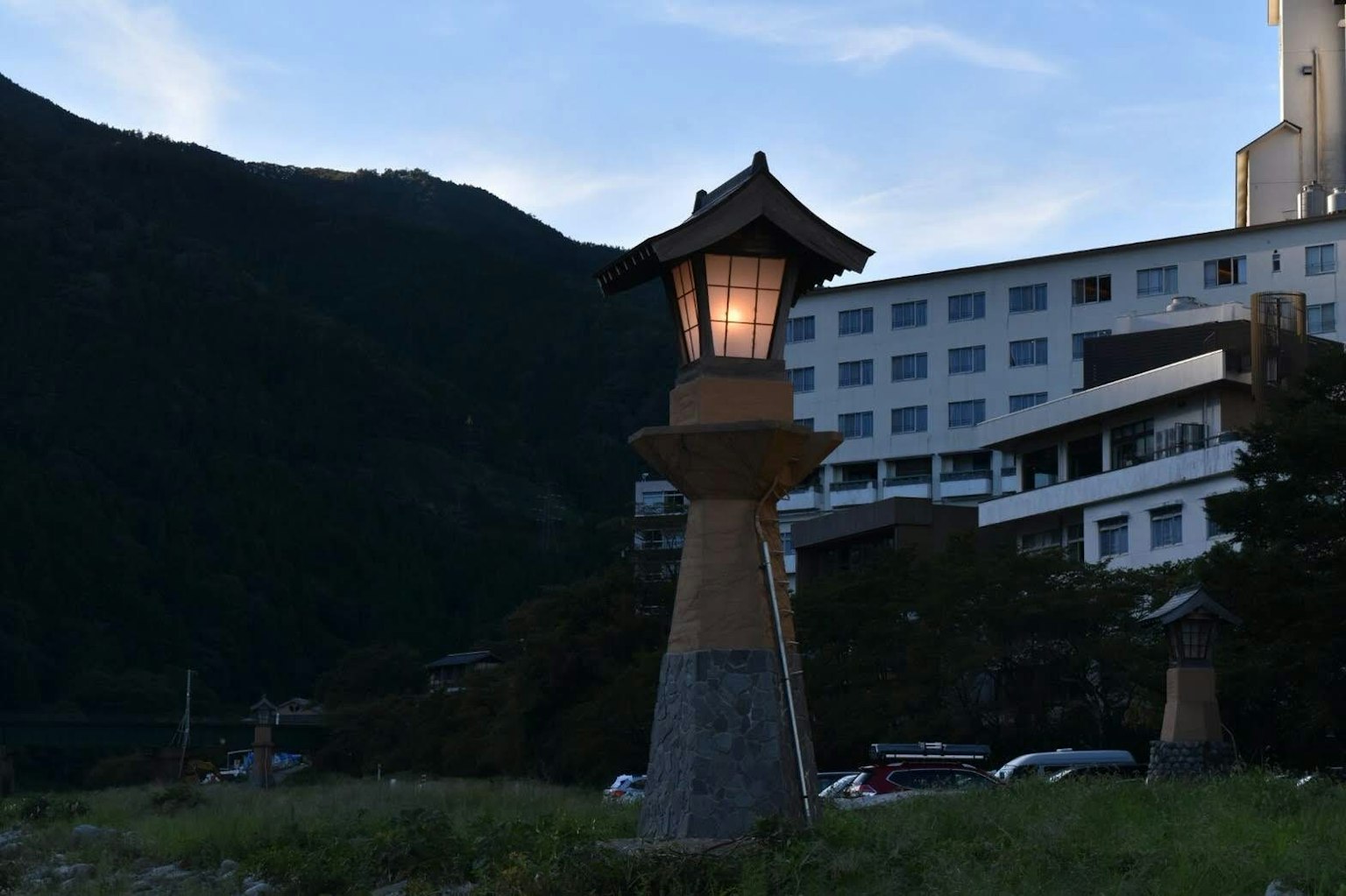 Lanterna in stile giapponese illuminata al crepuscolo con un hotel sullo sfondo