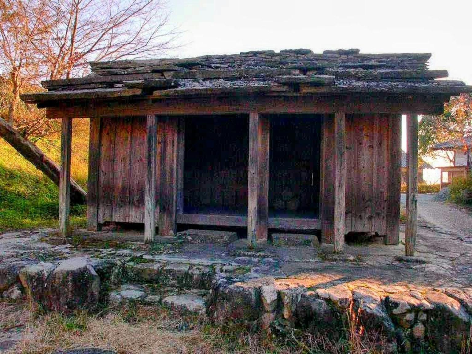 一座古老的木屋，屋頂磨損，石基礎