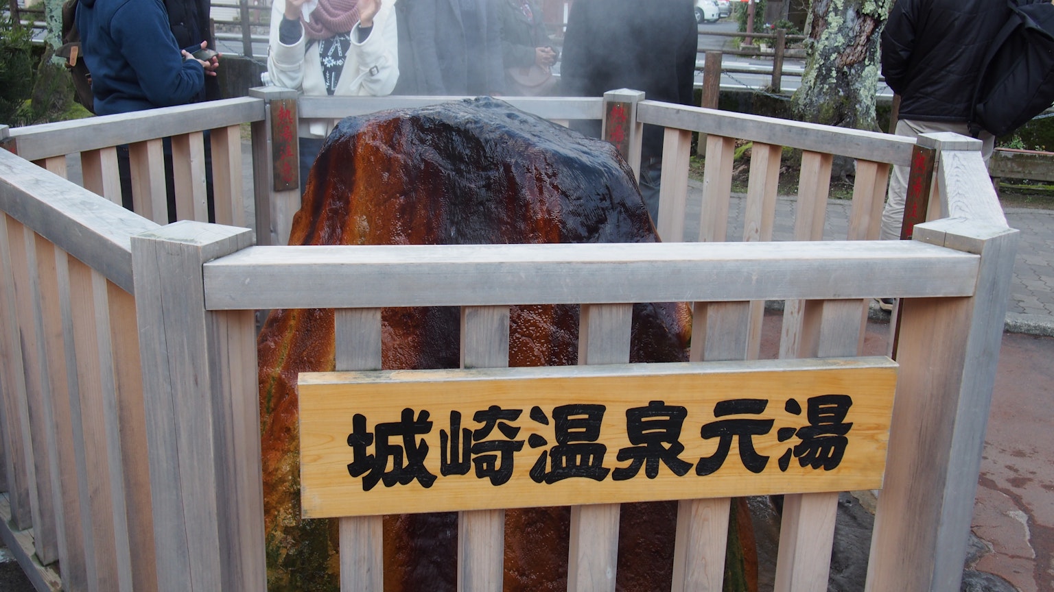 Sign of Kinosaki Onsen Genyu with steaming hot spring rock