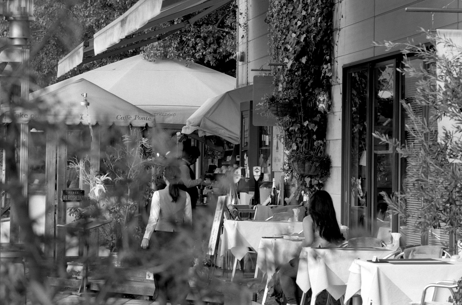 Photo en noir et blanc de personnes dînant sur une terrasse de café