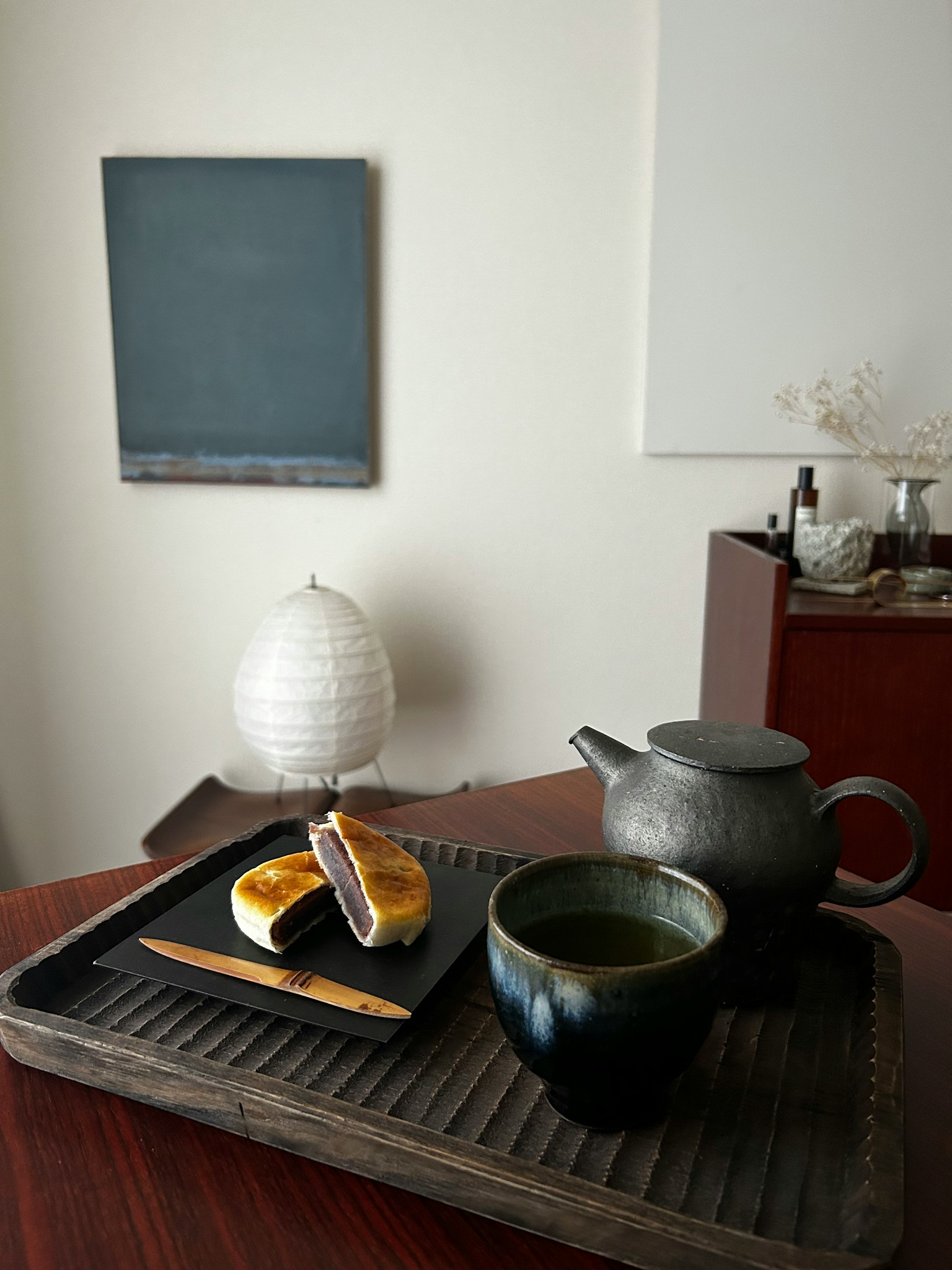 Un interior simple y sereno con una tetera, un cuenco de té y dulces japoneses sobre una mesa