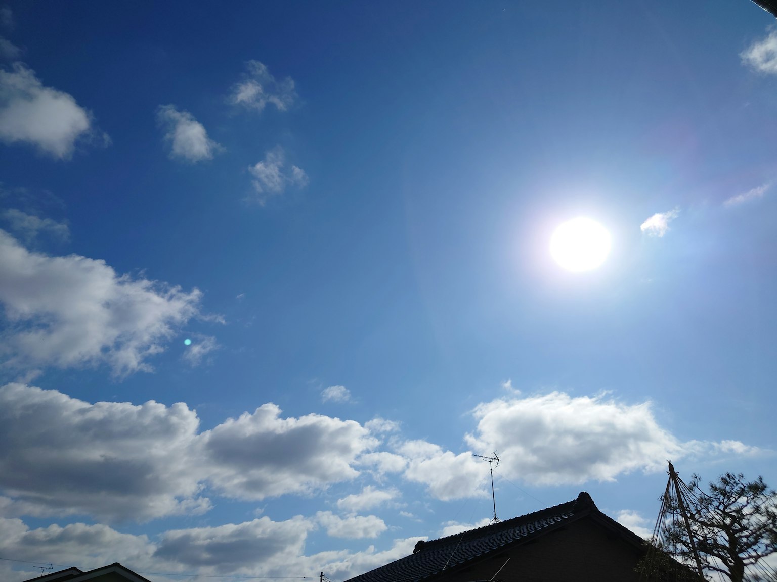 Langit biru cerah dengan awan putih dan matahari bersinar