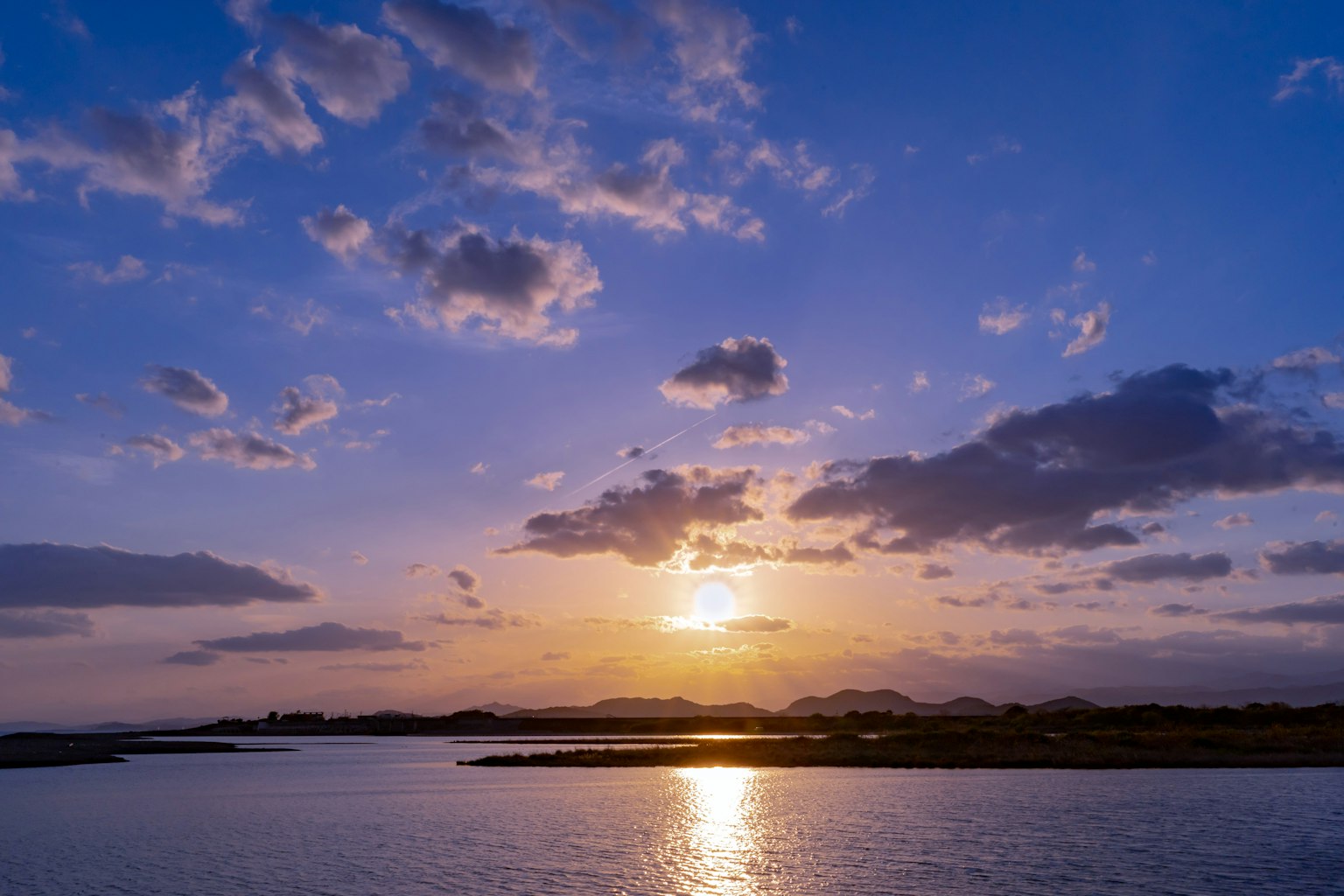 Tramonto su un fiume tranquillo con colori vivaci e nuvole
