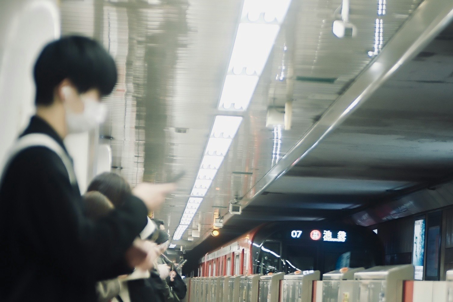 people seated on a platform bench with a tunnel-like station corridor depth