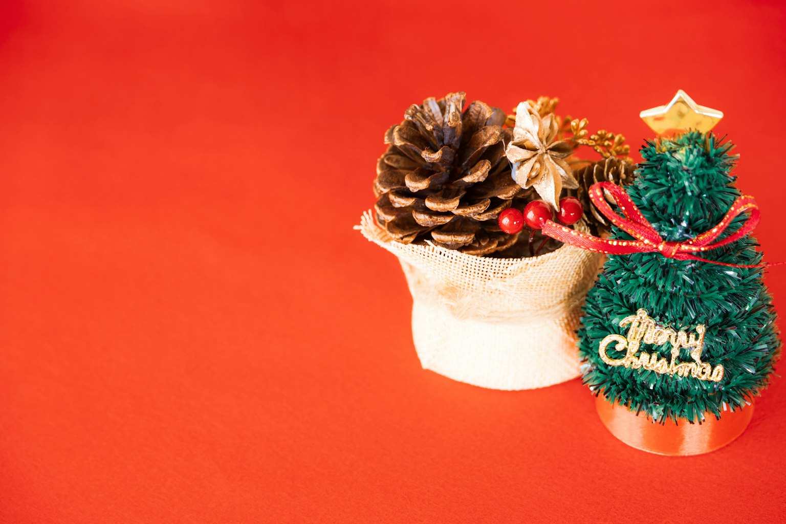 Pequeña decoración de árbol de Navidad y piña sobre fondo rojo