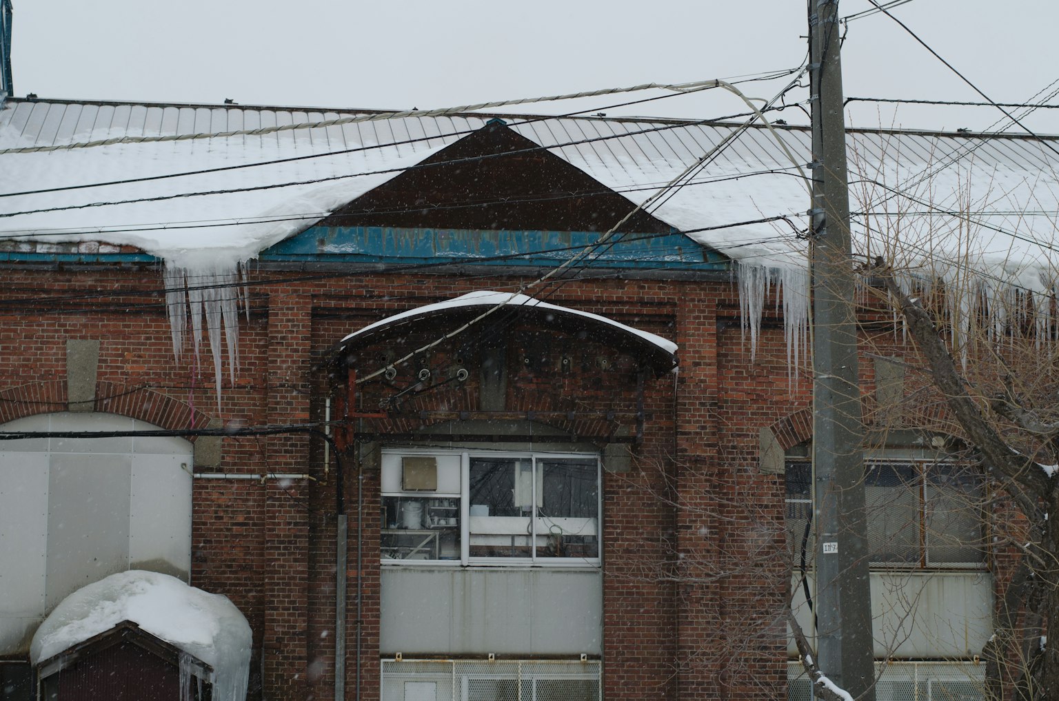 Ancien bâtiment en briques avec des stalactites de glace suspendues au toit recouvert de neige
