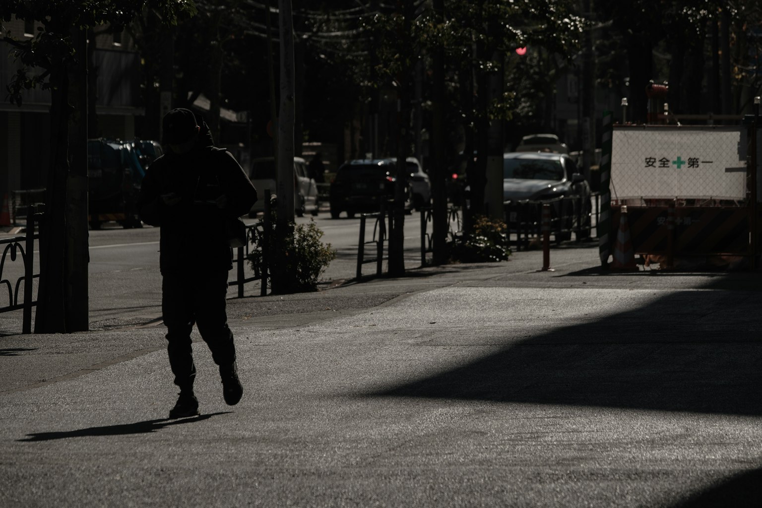 Eine Person, die im Schatten auf einer urbanen Straße läuft
