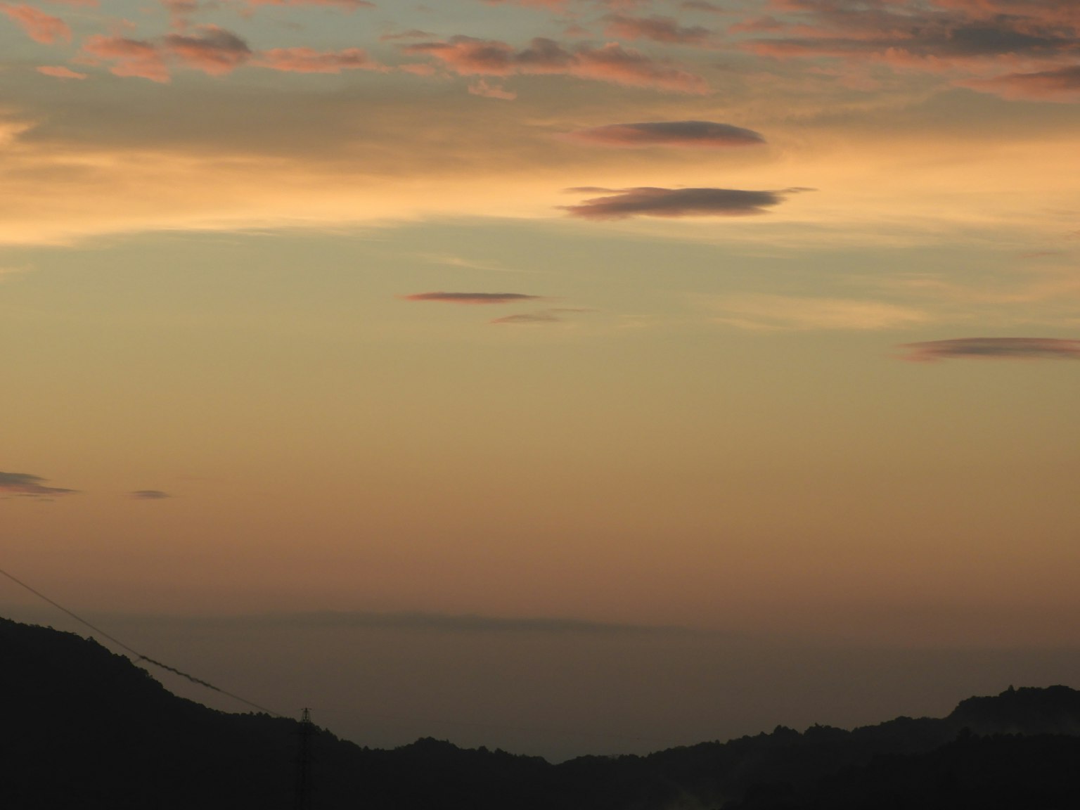 Cielo al tramonto con sfumature arancioni e rosa e silhouette di montagne