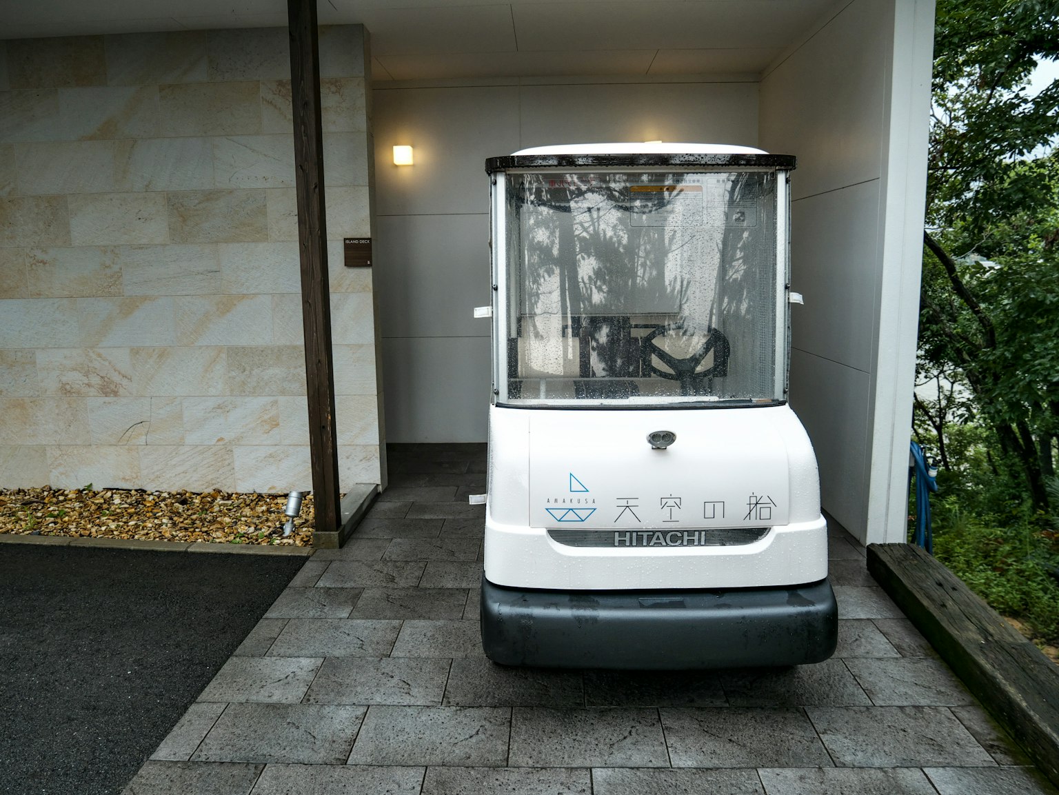 A small white vehicle with transparent windows parked in front of a doorway