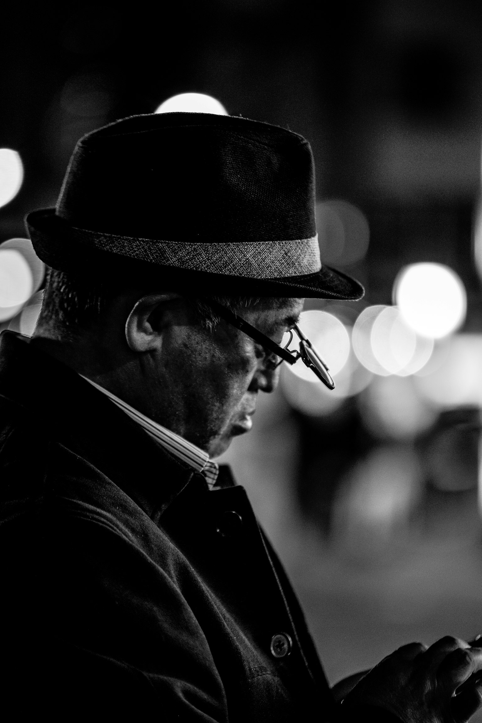 Un uomo con un cappello nero che guarda uno smartphone in un'immagine in bianco e nero