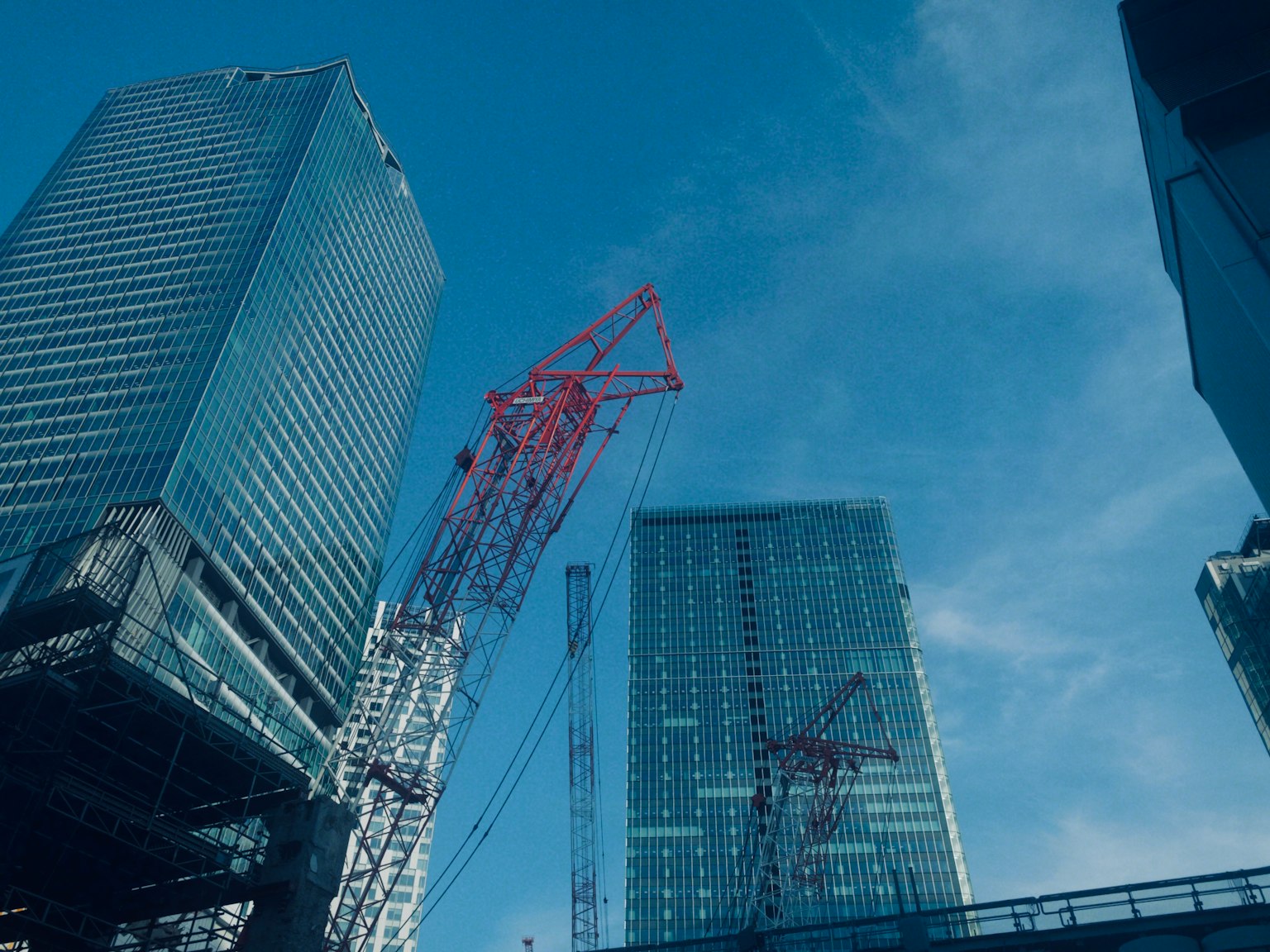 Chantier de construction avec des gratte-ciel et des grues rouges sous un ciel bleu