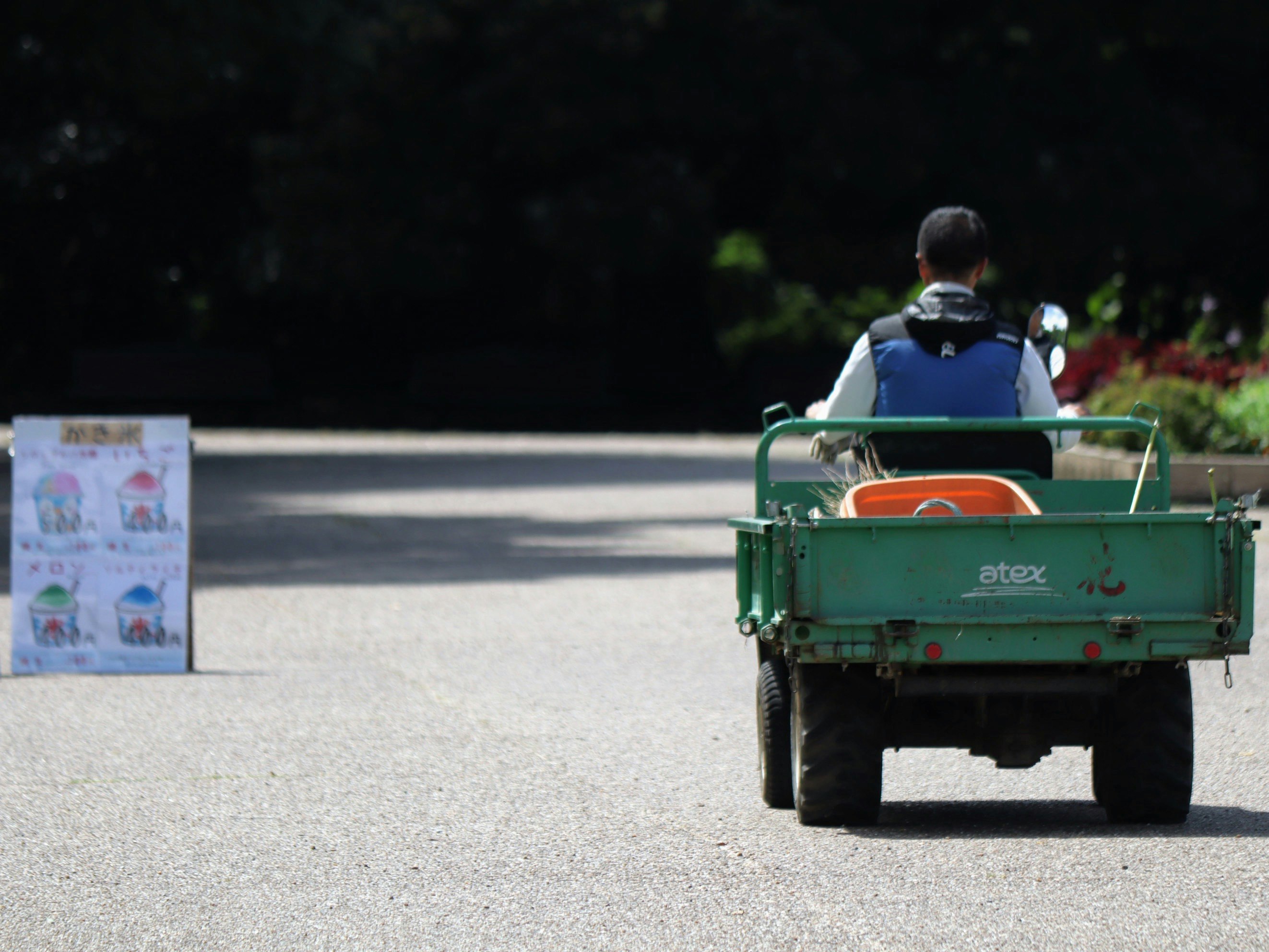 夏の暑い日に緑の荷台付き三輪車が走る公園の道