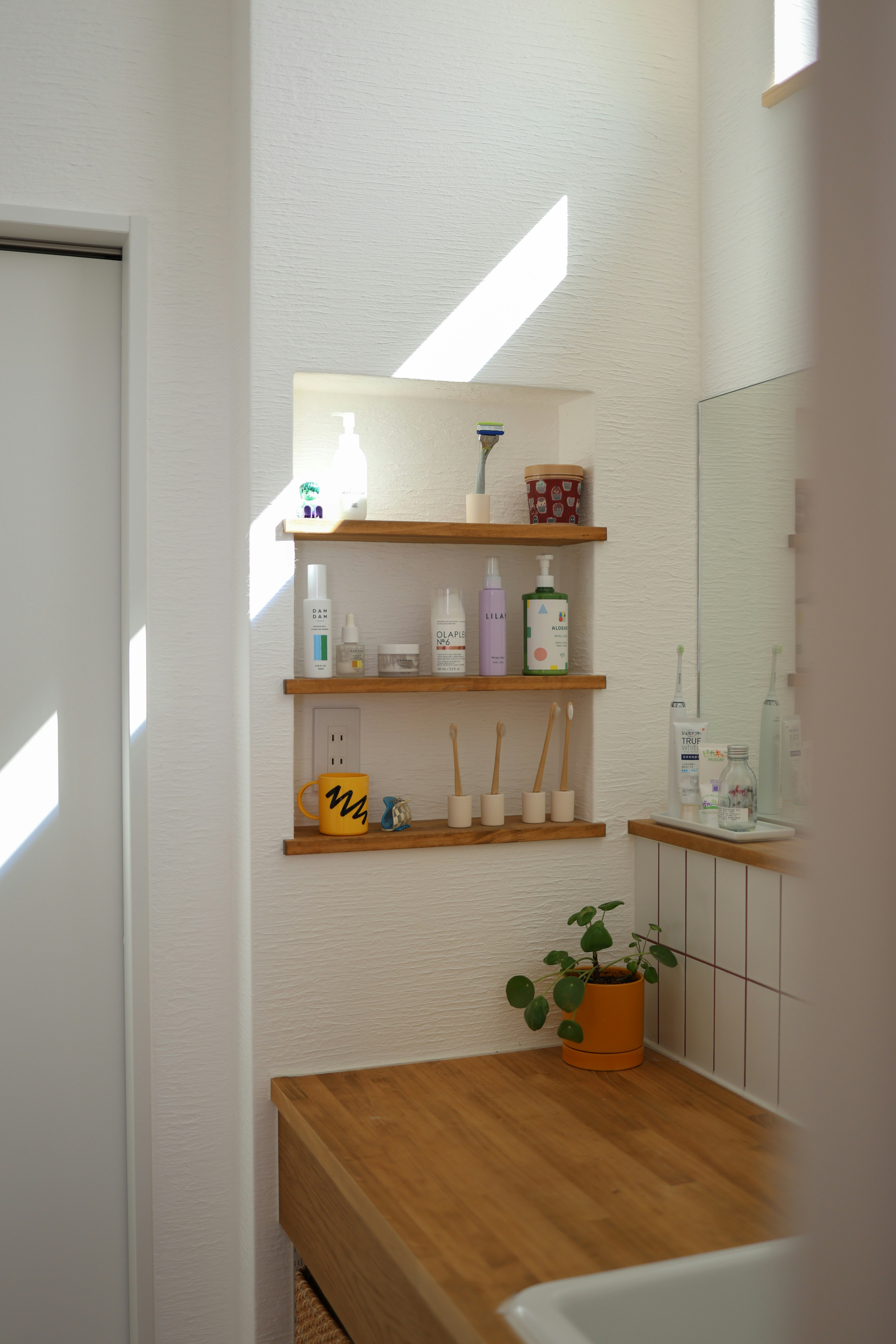 Étagère de salle de bain avec brosses à dents et produits d’hygiène buccale sur murs blancs
