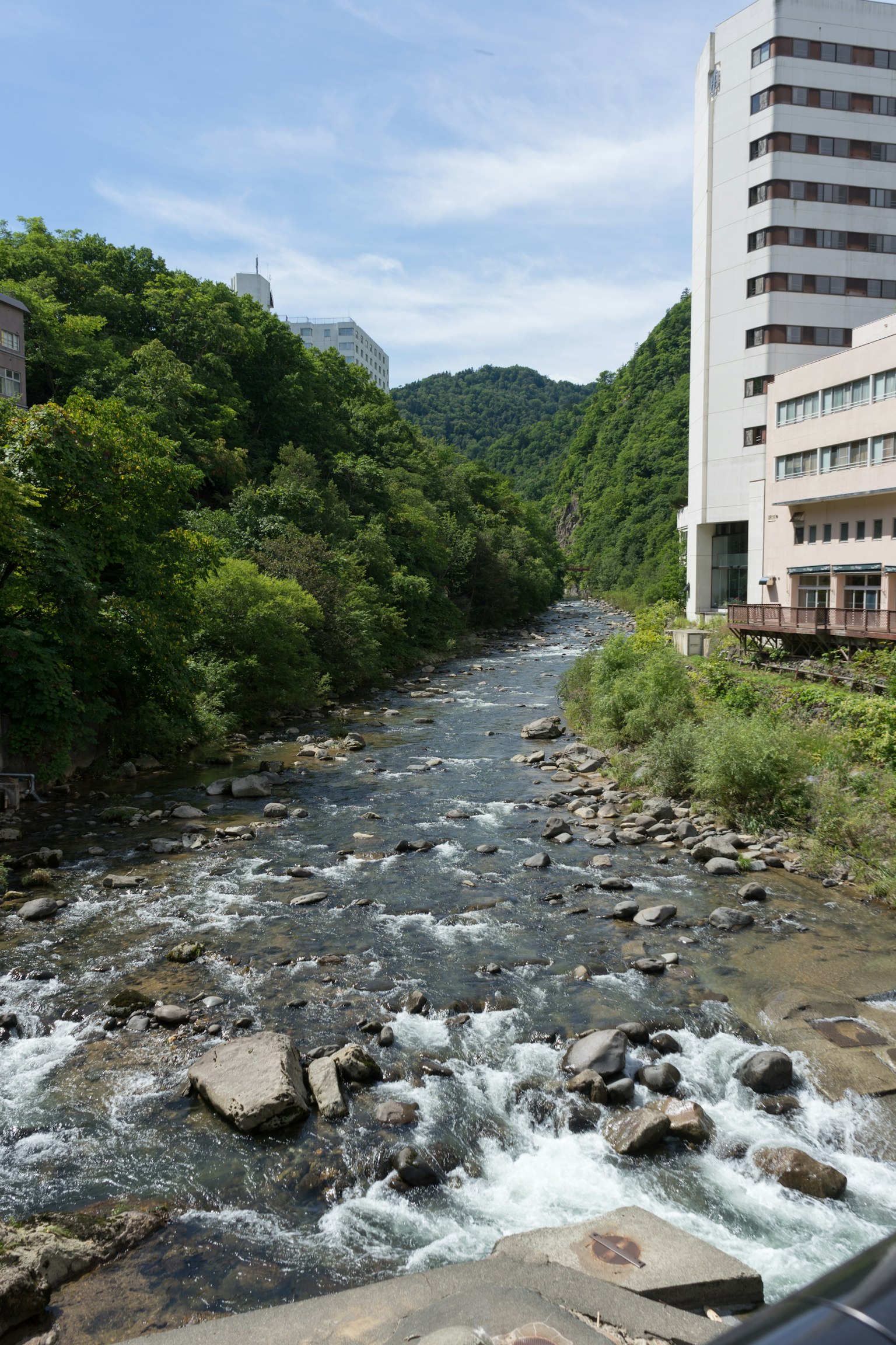 Malersicher Blick auf einen Fluss, umgeben von üppigen grünen Bergen und einem nahegelegenen Gebäude