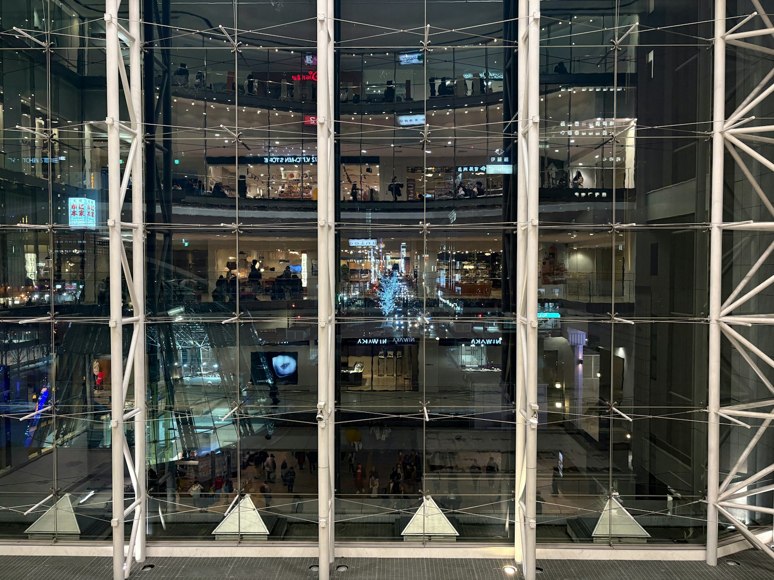 Vista interior de un edificio moderno con fachada de vidrio que refleja luces