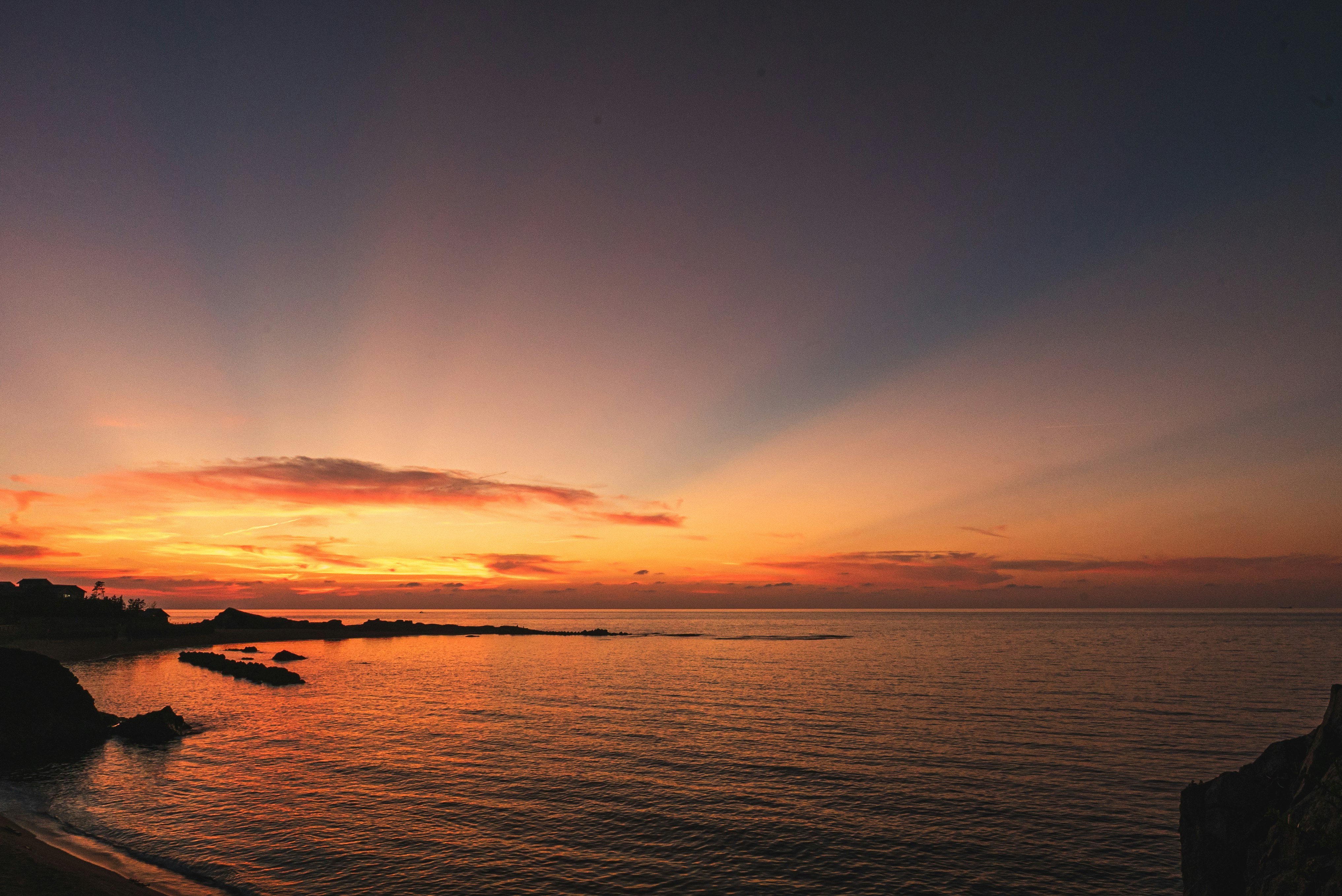 夕暮れの海岸線と水平線に広がる夕焼け空