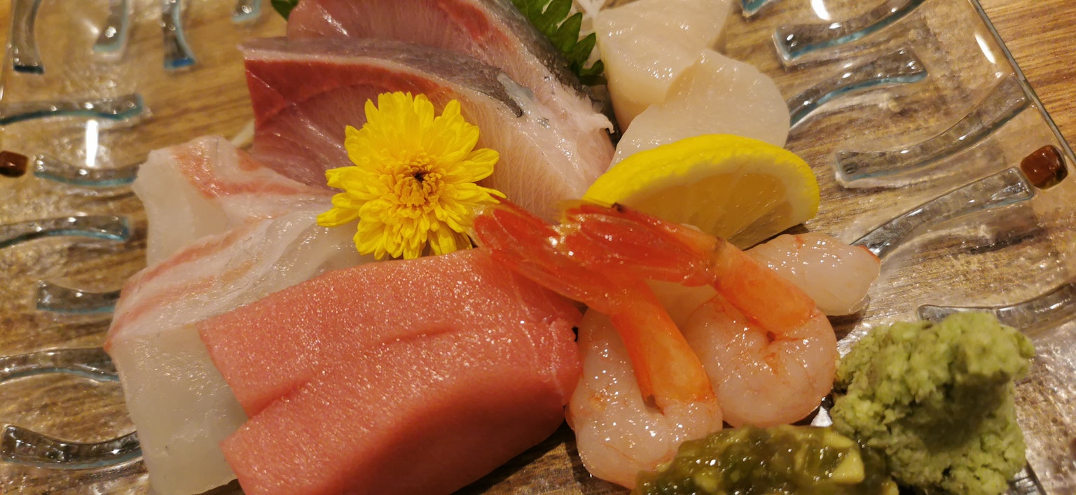 Un plateau de sashimi frais avec un assortiment de poissons garni d'une fleur jaune et de tranches de citron