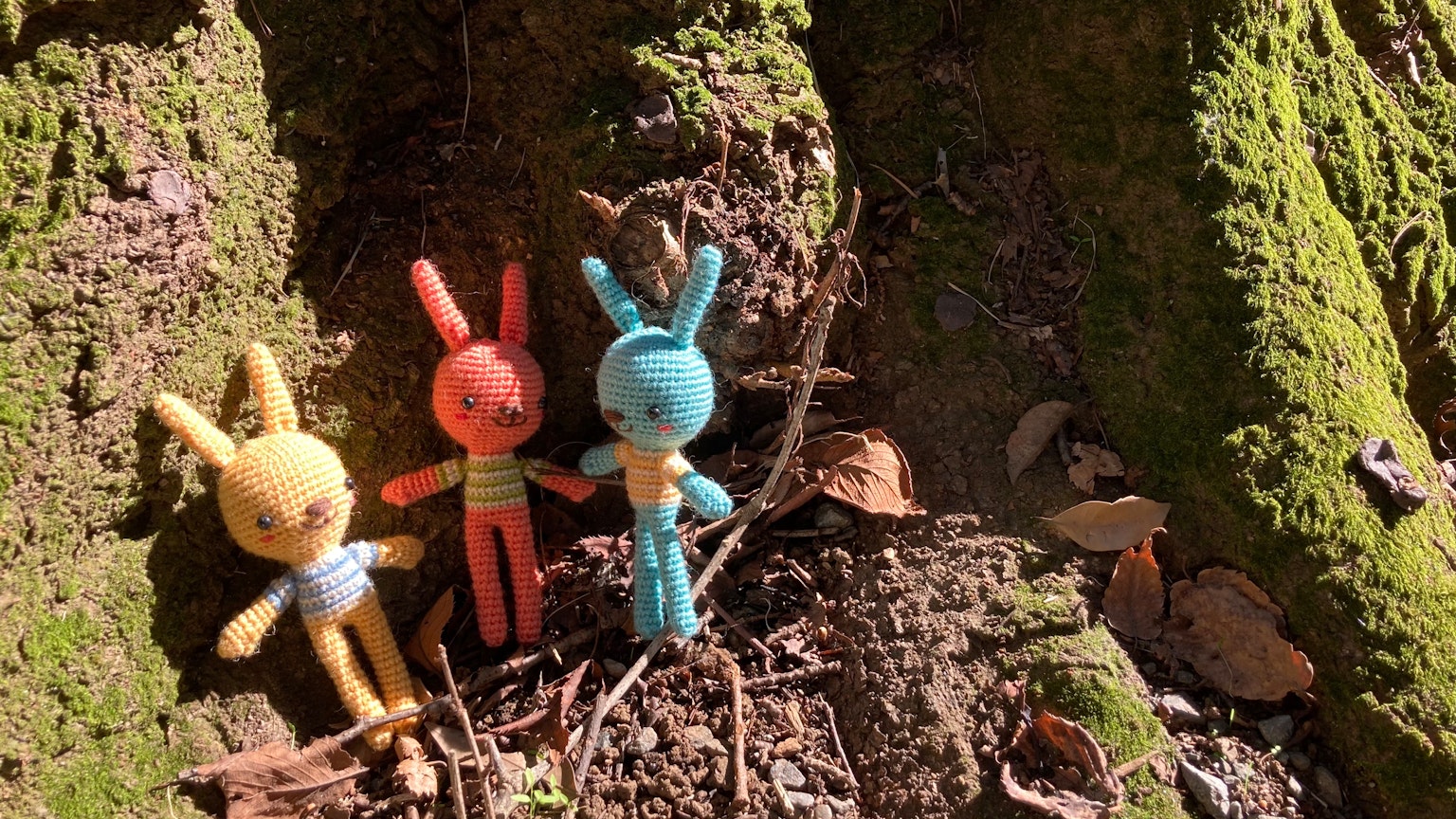 Figurine di conigli colorati in piedi alla base di un albero