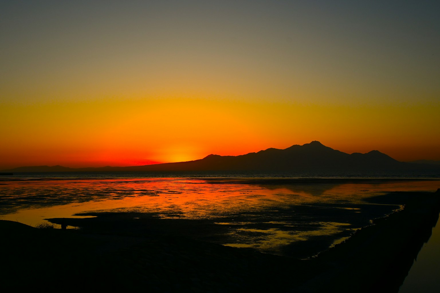 Sunset over the sea with mountain silhouette