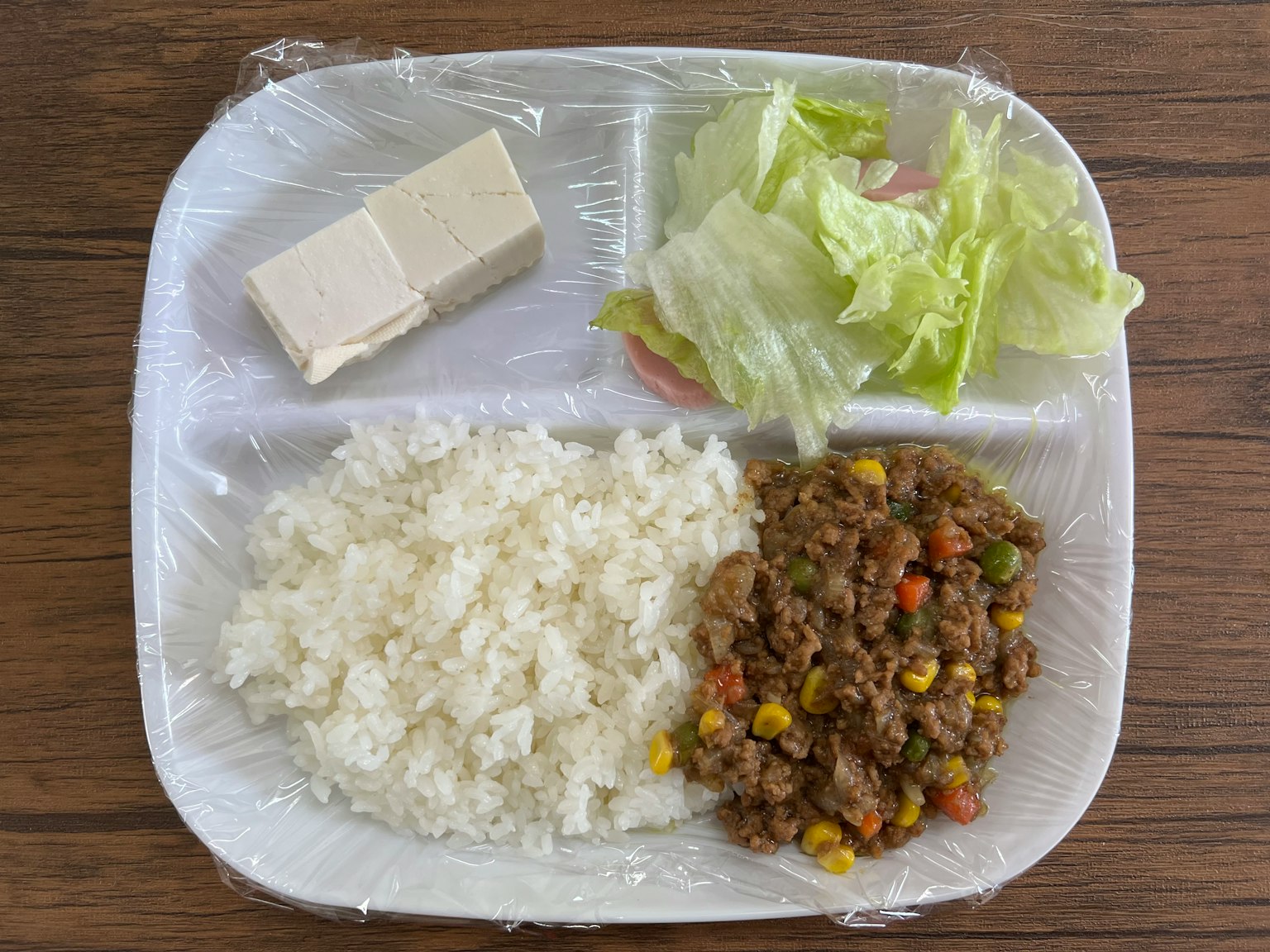 Assiette avec du riz blanc, salade de légumes, tofu et plat de viande hachée