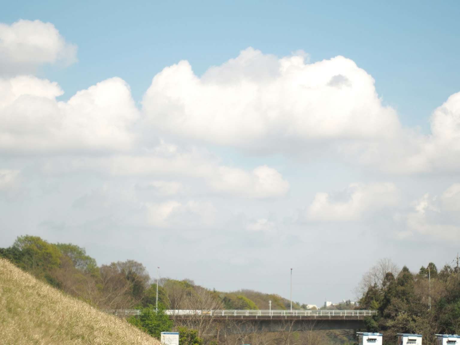 Vista escénica de un puente bajo un cielo azul con nubes blancas esponjosas