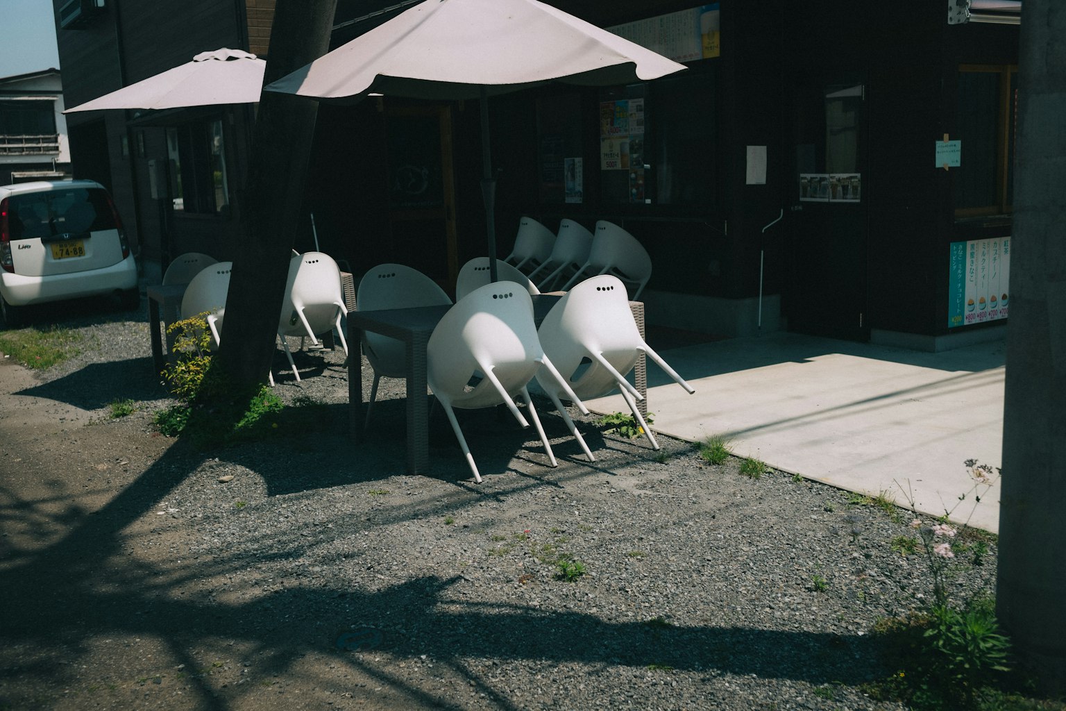 Outdoor terrace with white chairs and shaded umbrellas