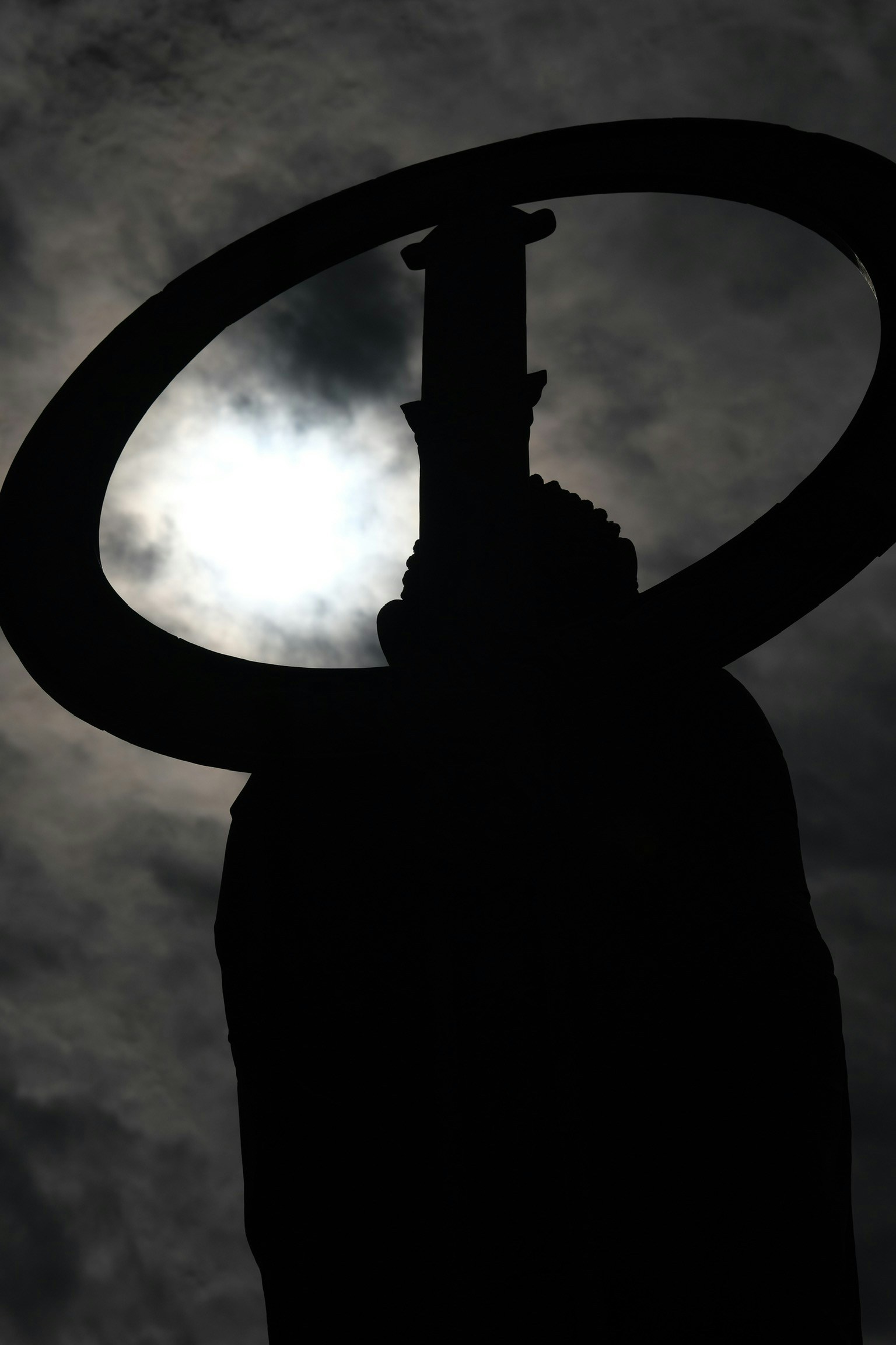 Silhouette of a statue with a halo against a dark background