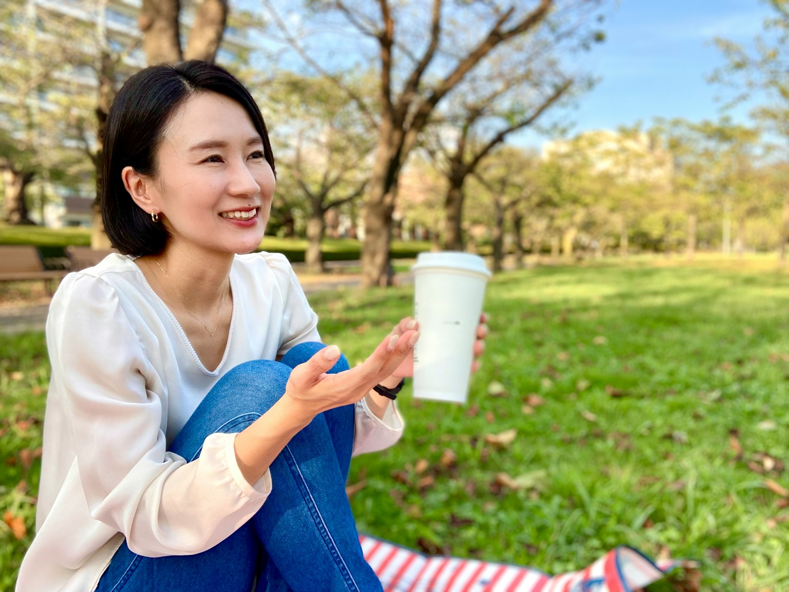 공원에서 커피를 들고 있는 젊은 여성 미소 짓고 편안한 모습