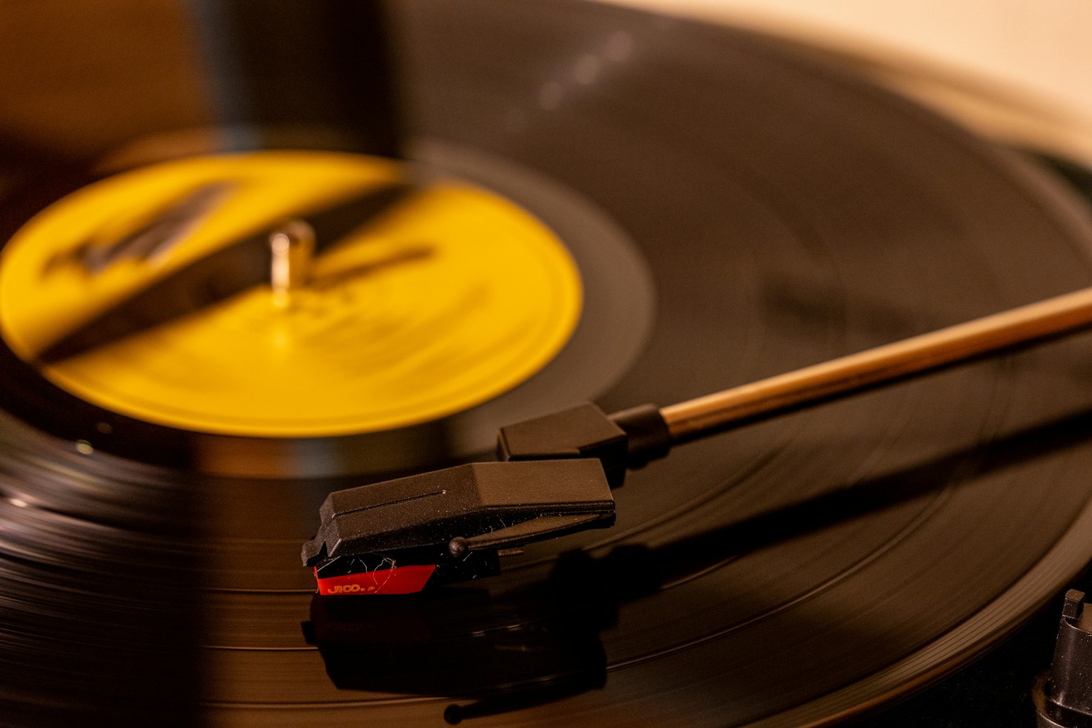 Close-up of a black vinyl record with a yellow label on a turntable