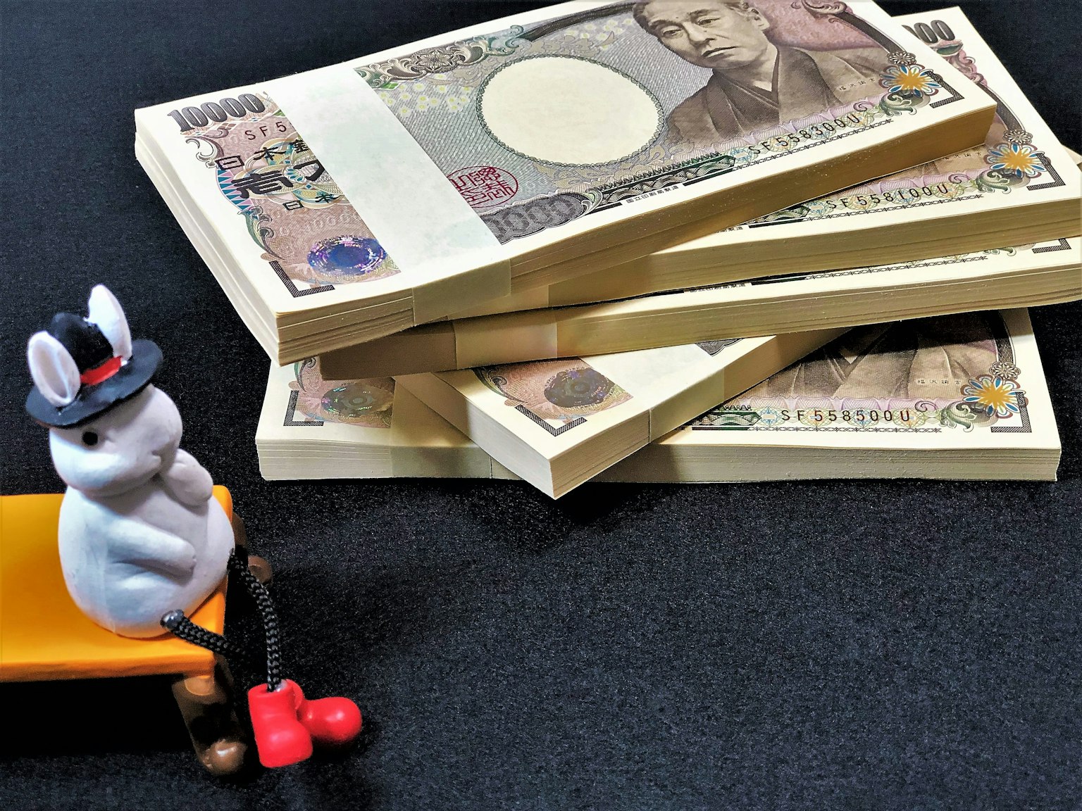 A small rabbit figurine sitting next to a stack of Japanese banknotes