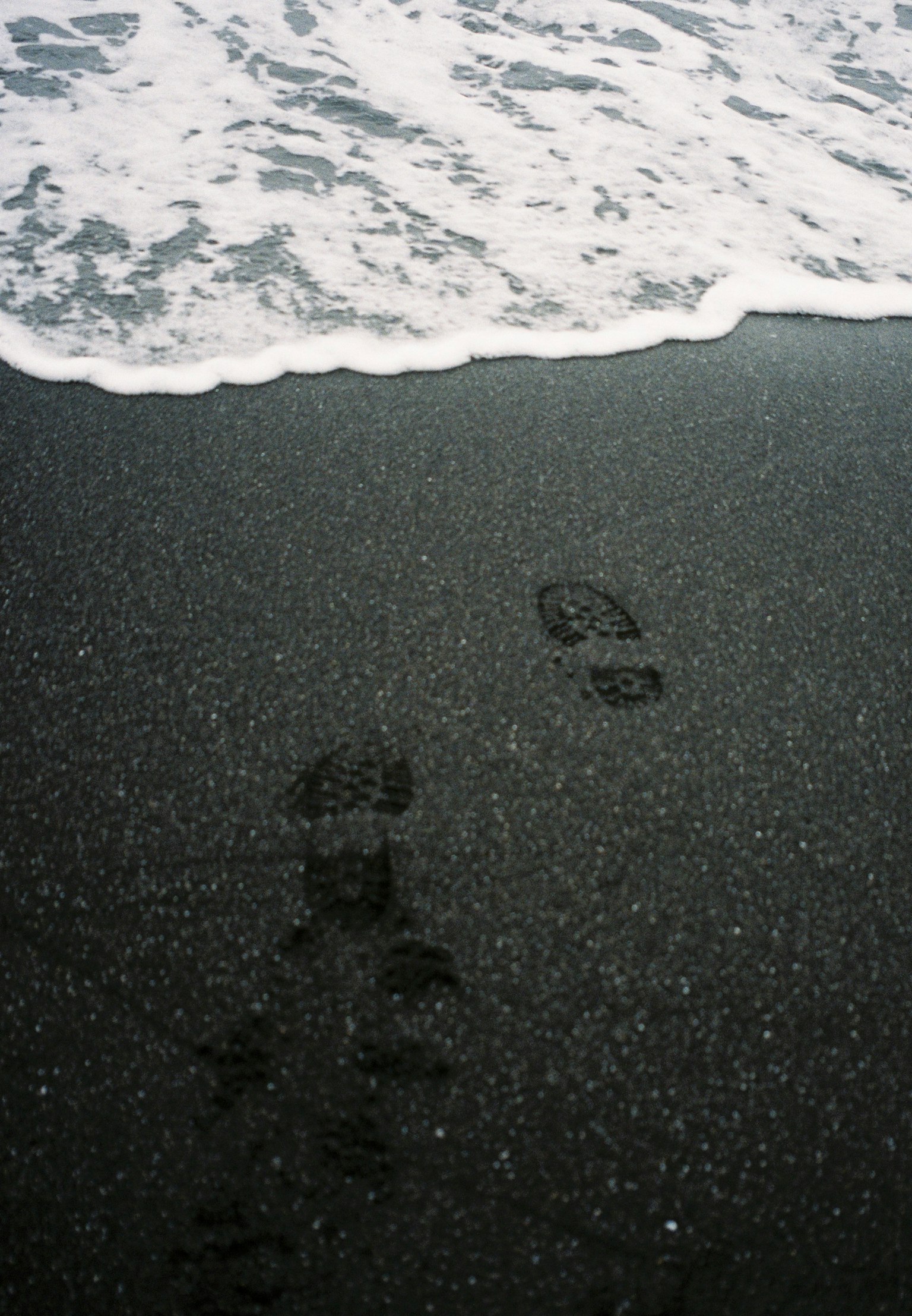 Empreintes de pas sur une plage de sable près des vagues