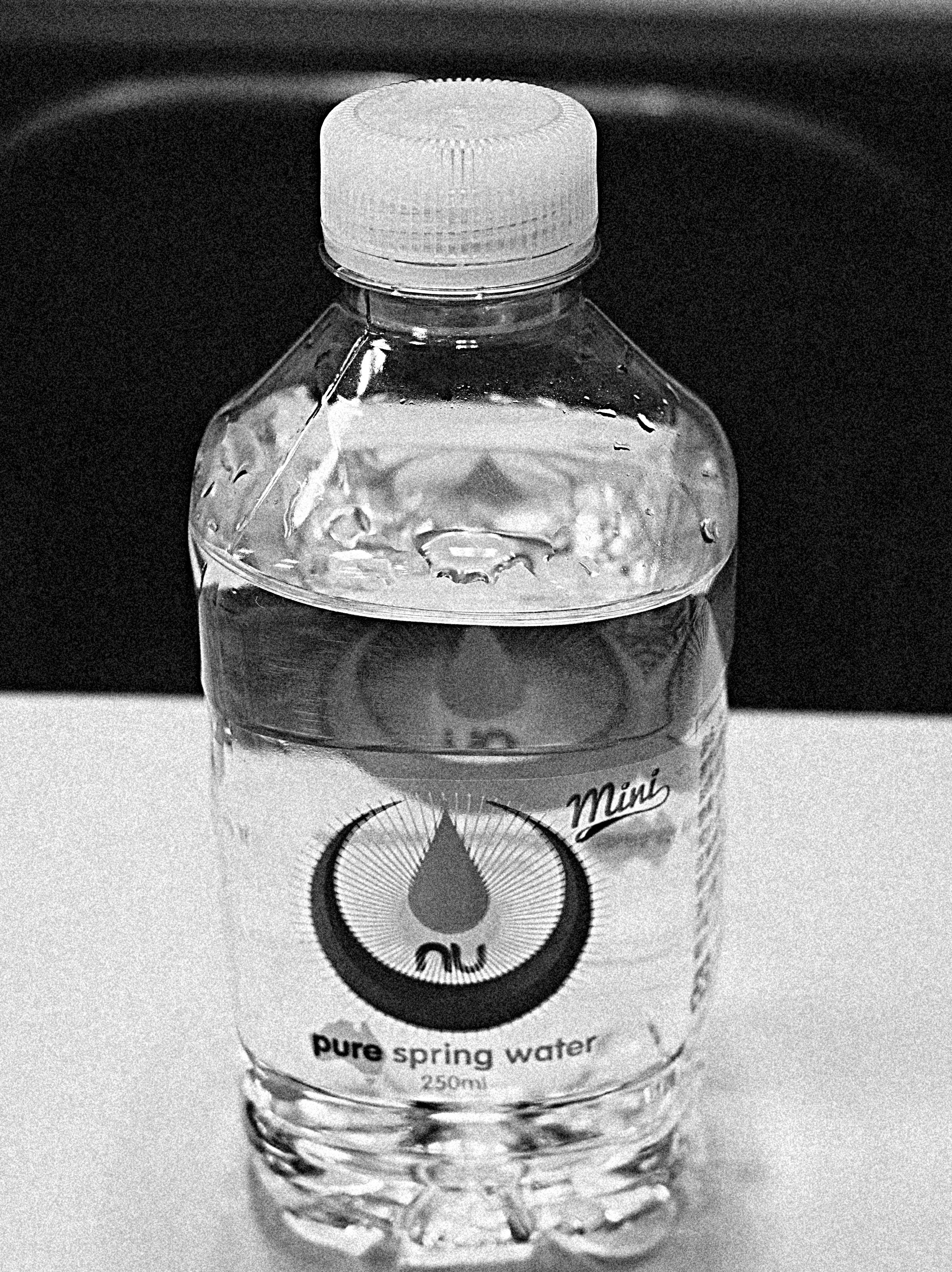 Botella de agua clara con una etiqueta que presenta un diseño de gota