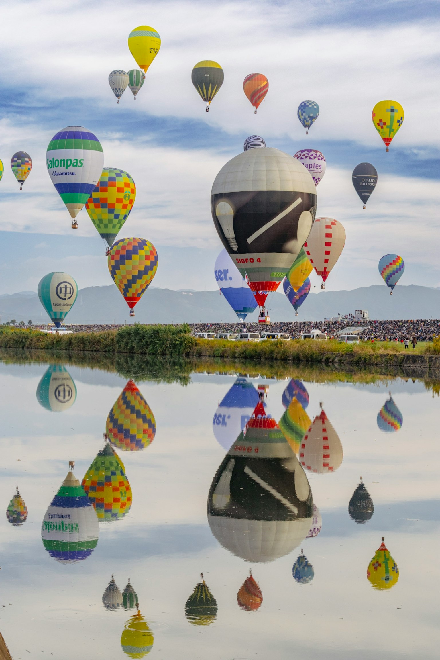 色とりどりの熱気球が空に浮かび水面に映る美しい風景
