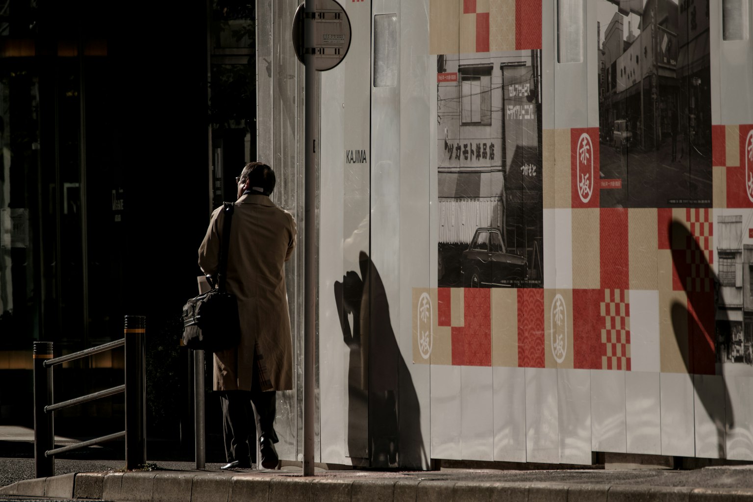 Scena urbana con una persona in piedi all'angolo di una strada e ombre marcate
