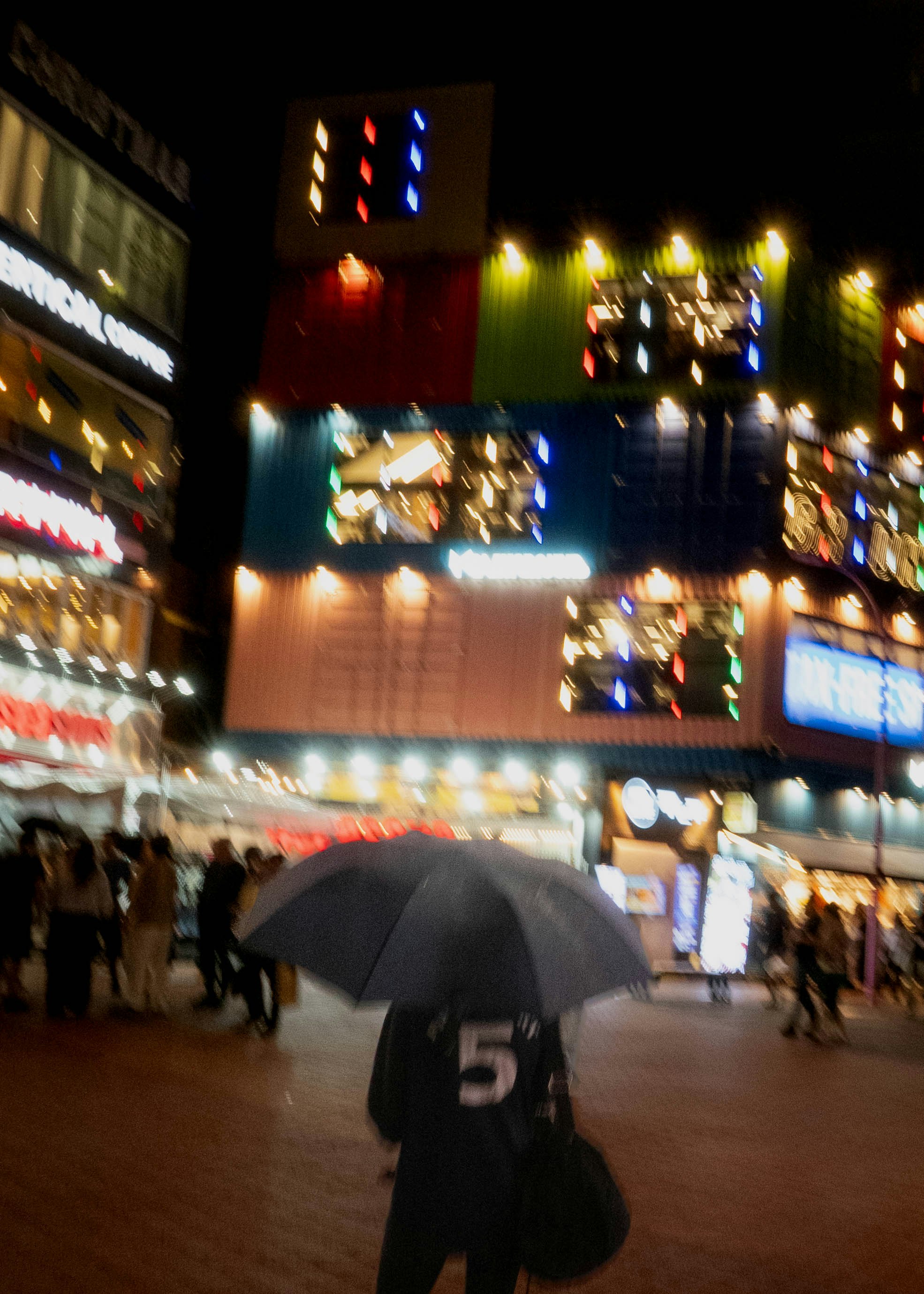 雨の夜のにぎやかな繁華街で傘をさす人々