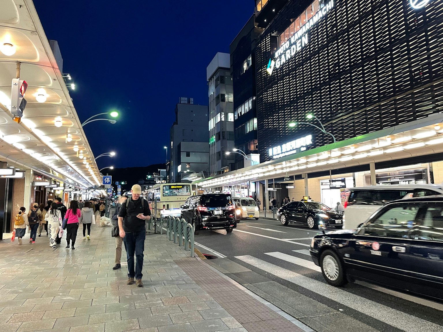 Des personnes marchant dans une rue de la ville la nuit avec des enseignes lumineuses