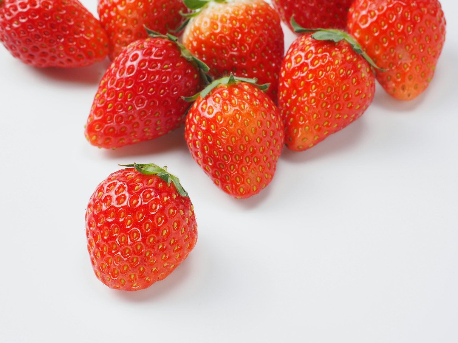 Fraises fraîches éparpillées sur un fond blanc