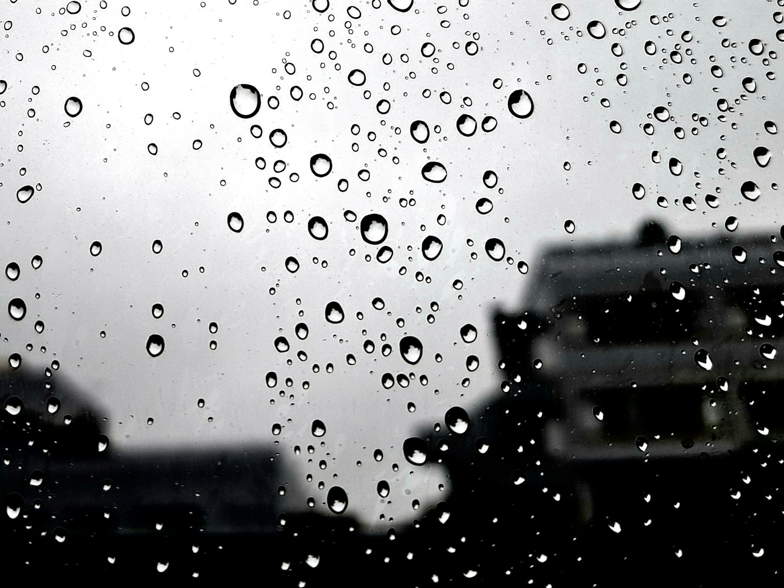 Giọt nước mưa trên cửa sổ với các tòa nhà mờ ở phía sau