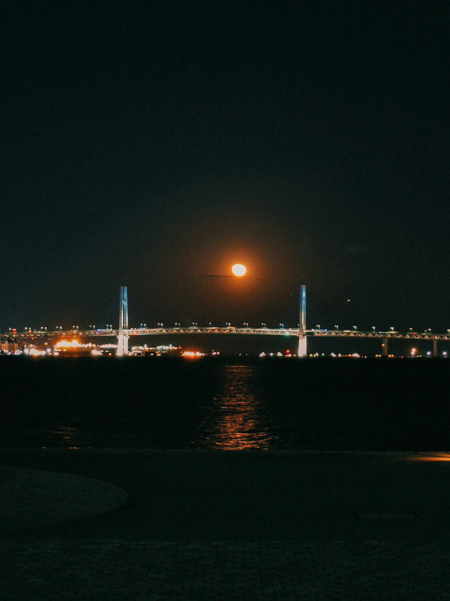 Beautiful view of a full moon above a bridge at night